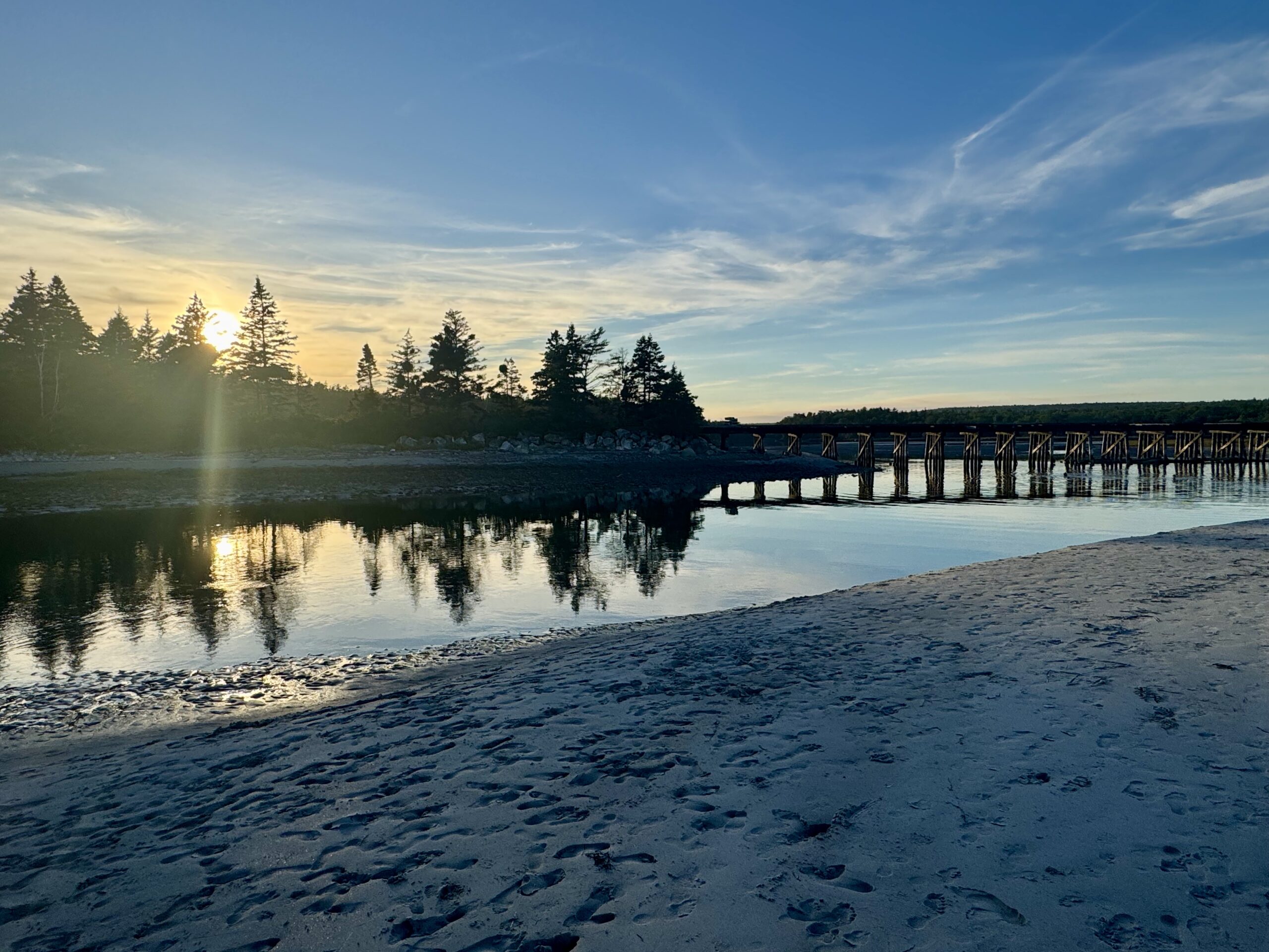 A bridge on a beach at sunset